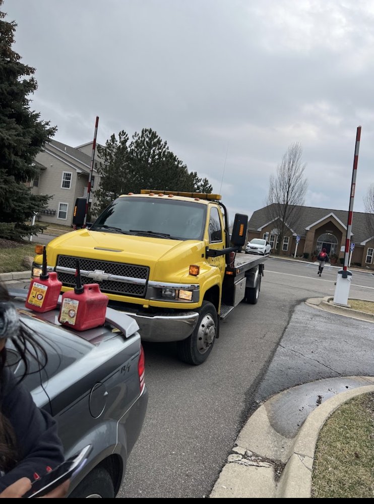 Yellow Charlie Towing flatbed arriving with fuel cans for a stranded driver