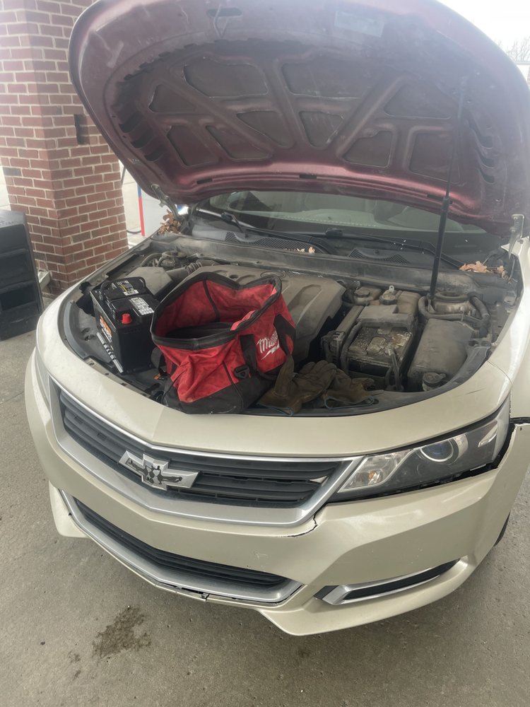 Technician replacing a car battery on a Chevrolet Impala roadside